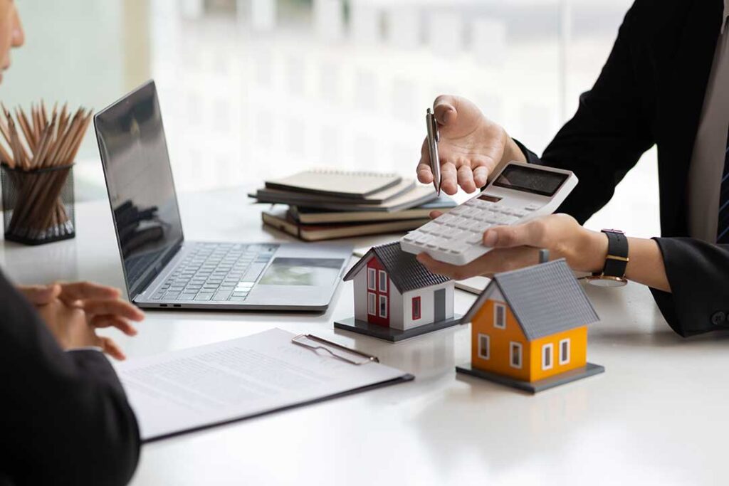 A young couple reviews paperwork with moving boxes in the background of a bright living room.